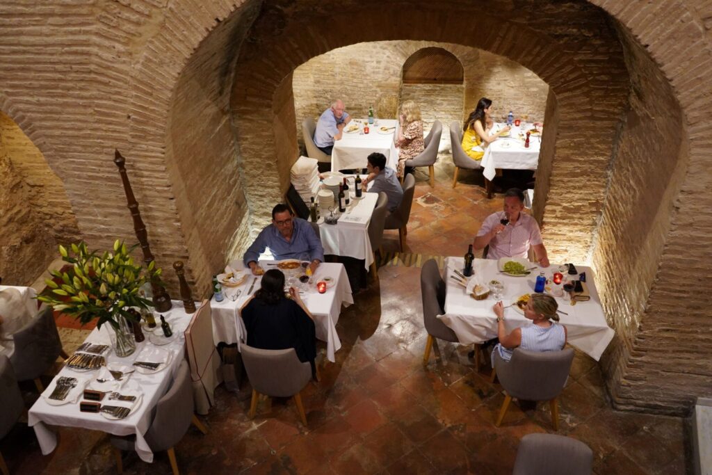DINERS ENJOYING MEALS IN A BRICK VAULTED RESTAURANT_Ash Nagrani